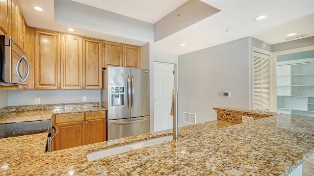 kitchen featuring appliances with stainless steel finishes, kitchen peninsula, and light stone counters