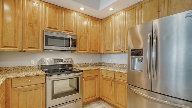 kitchen with light stone counters, stainless steel appliances, and light tile patterned floors