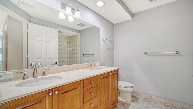 bathroom with a tile shower, tile patterned flooring, vanity, and toilet