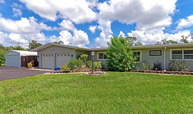 single story home featuring a garage, driveway, a front yard, and stucco siding