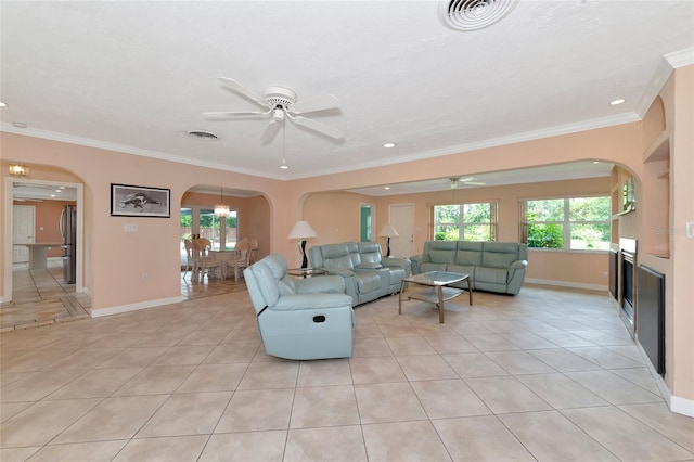 living area with ornamental molding, a wealth of natural light, light tile patterned flooring, and arched walkways