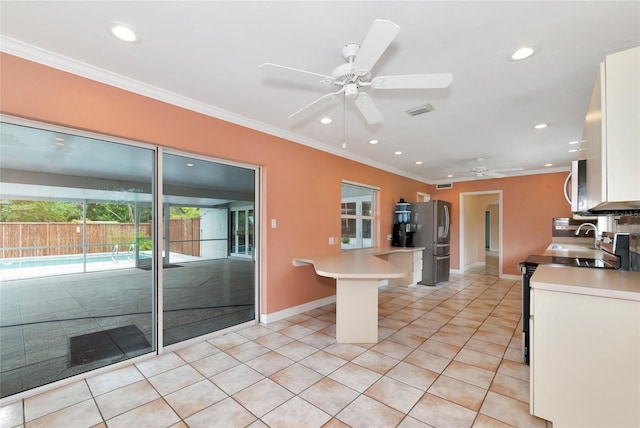 kitchen featuring light tile patterned floors, appliances with stainless steel finishes, ornamental molding, light countertops, and white cabinetry