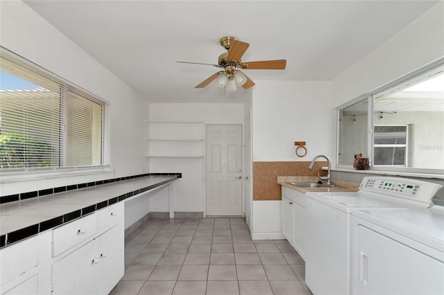 laundry room featuring light tile patterned floors, a sink, a ceiling fan, cabinet space, and washer and clothes dryer