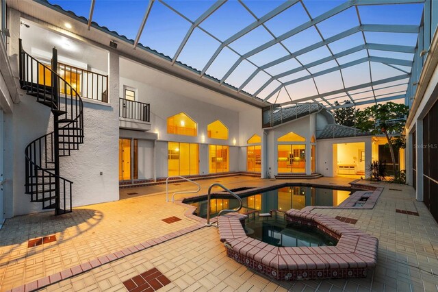 exterior space with a lanai, a swimming pool with hot tub, and a balcony