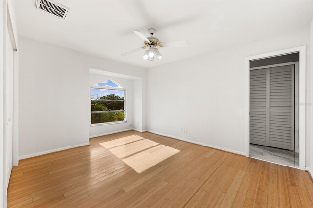 empty room with ceiling fan and light wood-type flooring