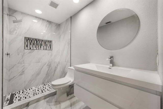 bathroom with vanity, toilet, and tiled shower