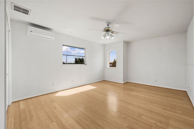 empty room featuring light hardwood / wood-style flooring, ceiling fan, and a wall mounted air conditioner