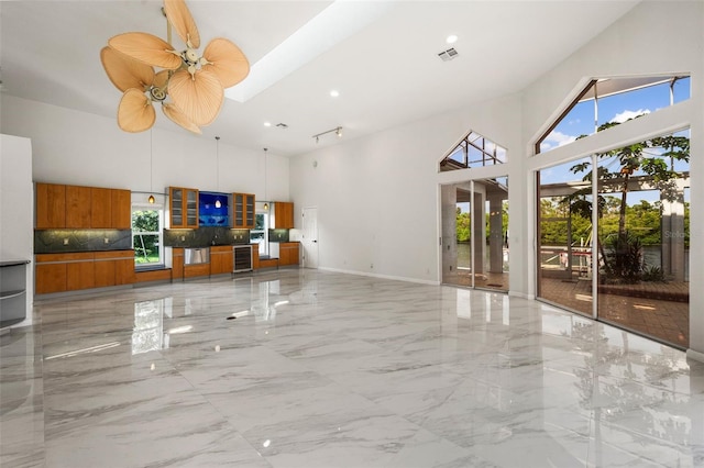 interior space with wine cooler, ceiling fan, and a high ceiling