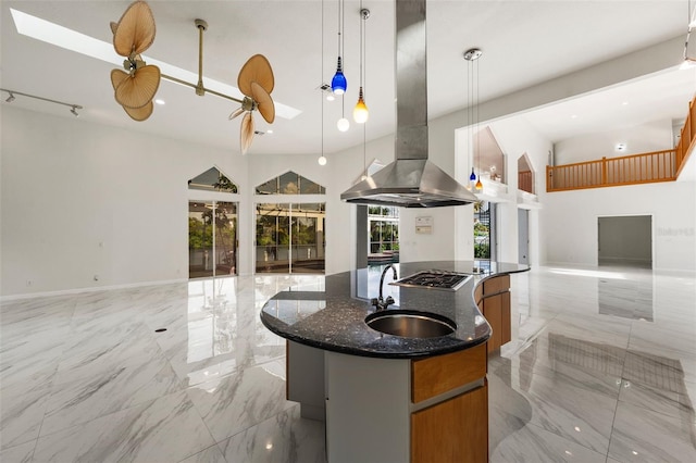 kitchen featuring dark stone counters, pendant lighting, sink, an island with sink, and island exhaust hood