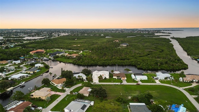 aerial view at dusk featuring a water view