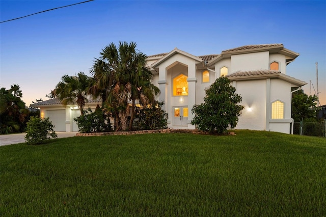 mediterranean / spanish-style house featuring a garage and a lawn