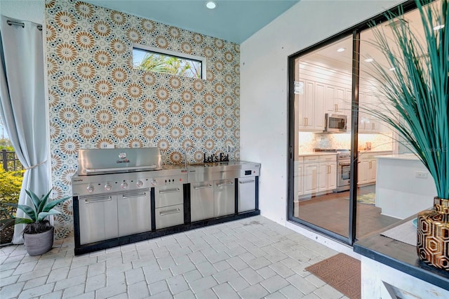 view of patio with exterior kitchen and a grill