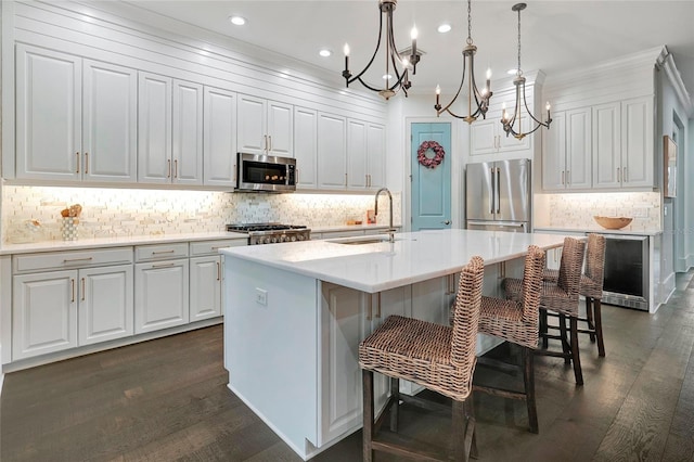 kitchen with an inviting chandelier, stainless steel appliances, sink, dark hardwood / wood-style floors, and ornamental molding