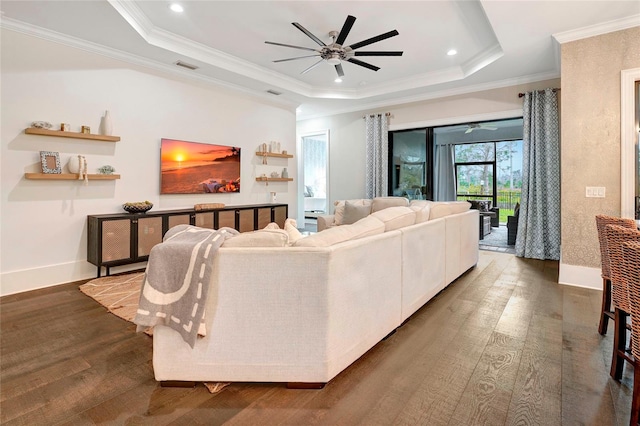 living room with ceiling fan, hardwood / wood-style flooring, a raised ceiling, and crown molding