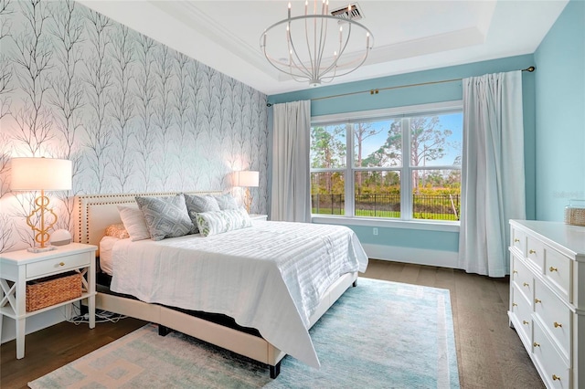 bedroom with a raised ceiling, an inviting chandelier, and dark hardwood / wood-style floors