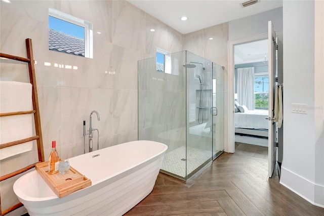 bathroom with tile walls, separate shower and tub, a baseboard radiator, and parquet flooring