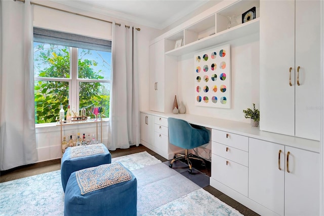 office space featuring crown molding, built in desk, and dark wood-type flooring