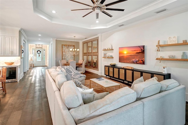 living room with ceiling fan with notable chandelier, a raised ceiling, crown molding, and dark wood-type flooring