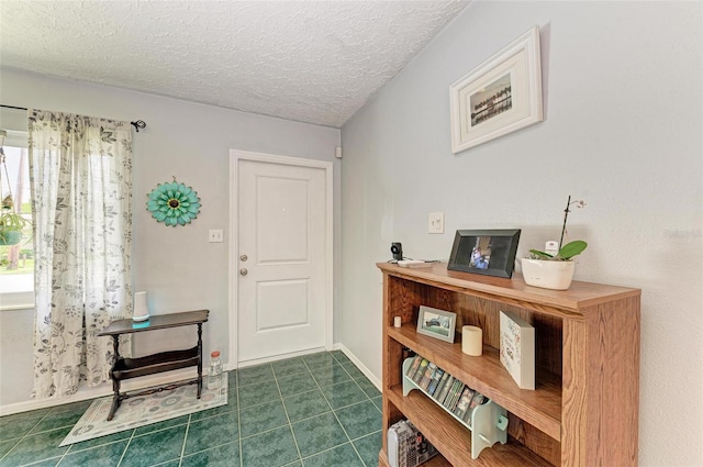 foyer featuring a textured ceiling, baseboards, and tile patterned floors