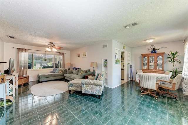 living room with dark tile patterned flooring, visible vents, and a textured ceiling