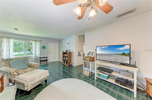 tiled living area featuring a ceiling fan, visible vents, a textured ceiling, and baseboards