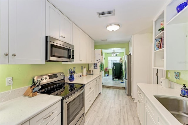 kitchen with stainless steel appliances, visible vents, light wood-style floors, white cabinetry, and open shelves