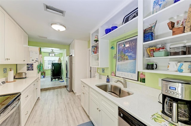 kitchen featuring light wood-style flooring, stainless steel appliances, a sink, visible vents, and open shelves