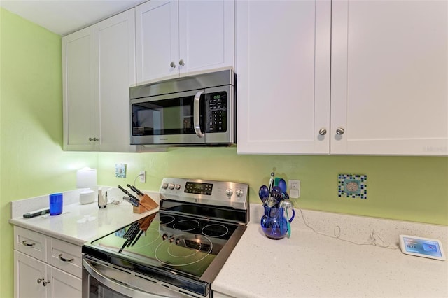 kitchen with stainless steel appliances, light stone countertops, and white cabinets