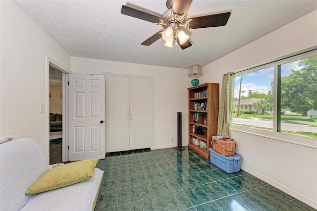 interior space featuring a textured ceiling, a closet, a ceiling fan, and baseboards