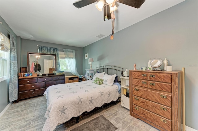 bedroom with baseboards, wood finished floors, visible vents, and a ceiling fan