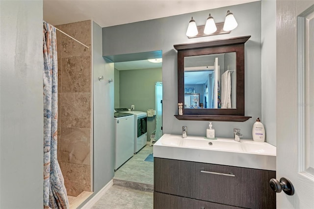 bathroom with tiled shower, washer and clothes dryer, vanity, and baseboards