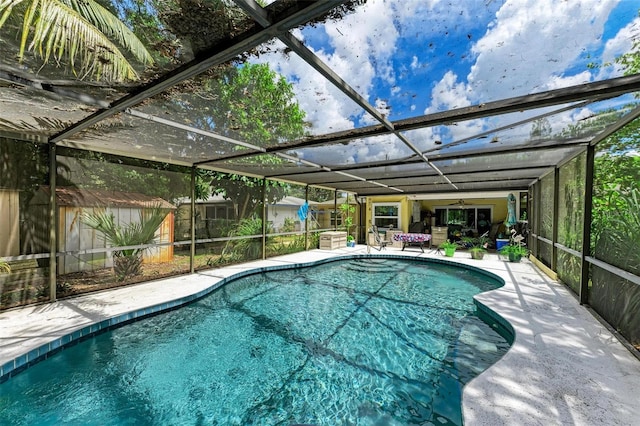 outdoor pool featuring an outbuilding, a storage unit, a patio area, and a lanai