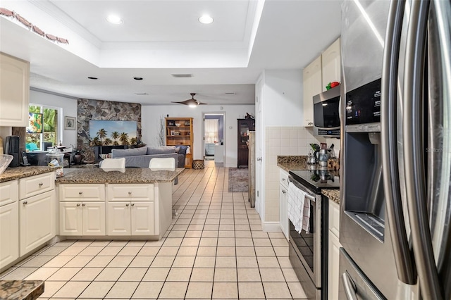 kitchen with stainless steel appliances, ceiling fan, a stone fireplace, stone countertops, and light tile patterned flooring