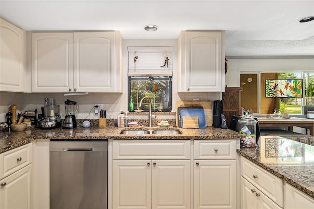 kitchen with dark stone countertops, dishwasher, backsplash, and sink