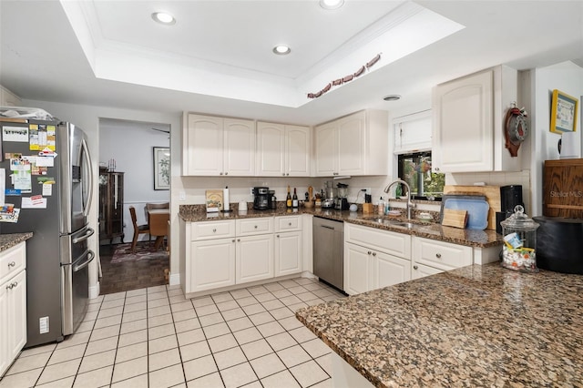 kitchen featuring a tray ceiling, stainless steel appliances, dark stone counters, and white cabinetry