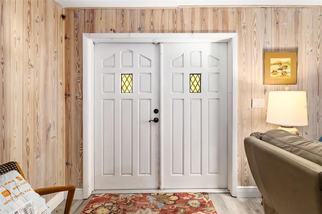 doorway to outside featuring wooden walls and light hardwood / wood-style floors