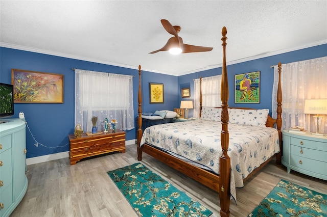 bedroom featuring light wood-type flooring, ornamental molding, ceiling fan, and a textured ceiling