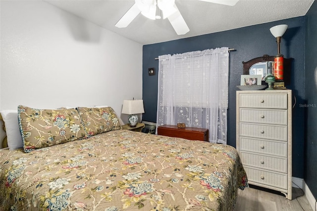 bedroom with ceiling fan, hardwood / wood-style flooring, and a textured ceiling