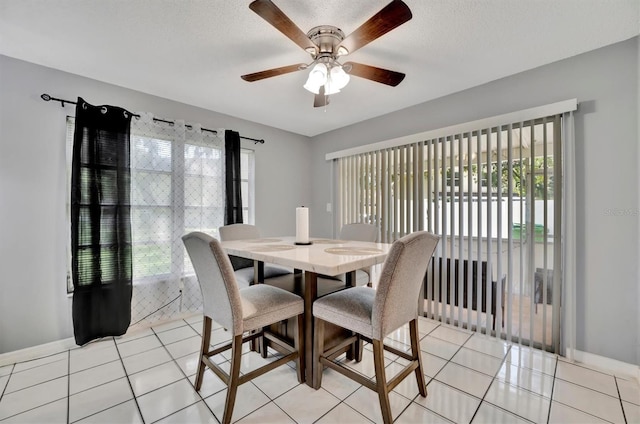 tiled dining space with a textured ceiling, plenty of natural light, and ceiling fan