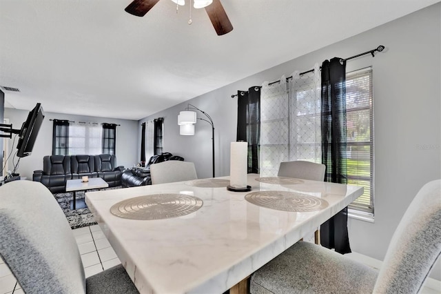 tiled dining space with a healthy amount of sunlight and ceiling fan