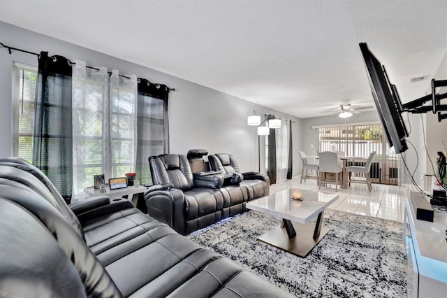 living room with a textured ceiling, ceiling fan, and tile patterned floors