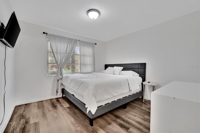 bedroom featuring a textured ceiling and wood-type flooring