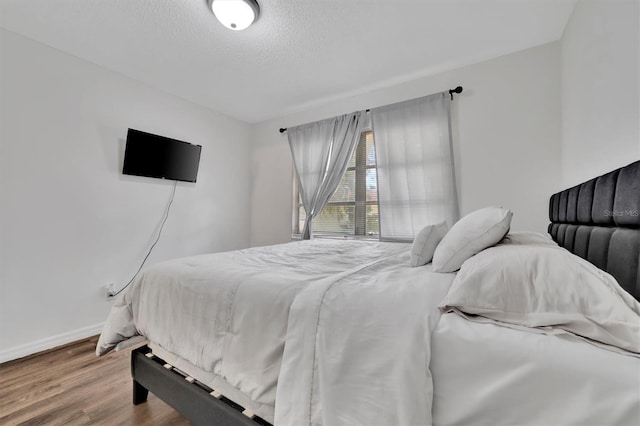 bedroom with a textured ceiling and light hardwood / wood-style floors