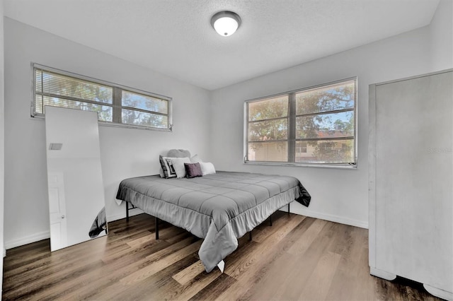 bedroom with multiple windows, wood-type flooring, and a textured ceiling