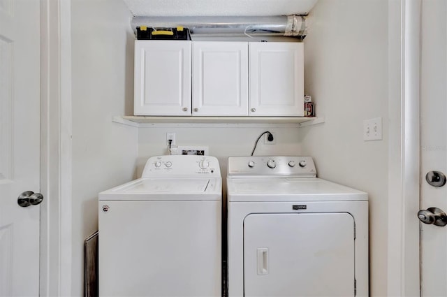 clothes washing area featuring cabinets and washing machine and dryer