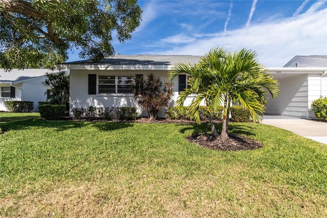 single story home featuring a carport, concrete driveway, a front yard, and stucco siding