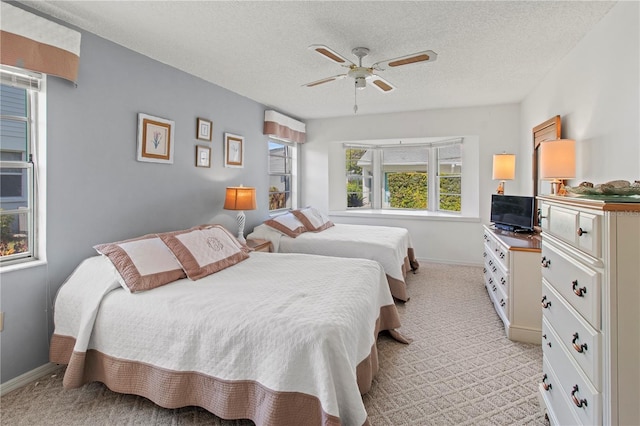 carpeted bedroom featuring ceiling fan and a textured ceiling