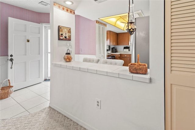 kitchen with hanging light fixtures, light tile patterned floors, and tile counters