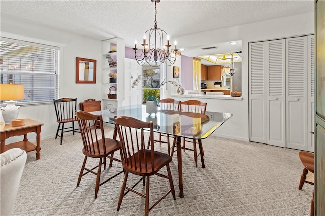 dining space with light colored carpet, a notable chandelier, and a textured ceiling