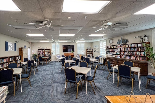 carpeted dining room featuring ceiling fan and a drop ceiling